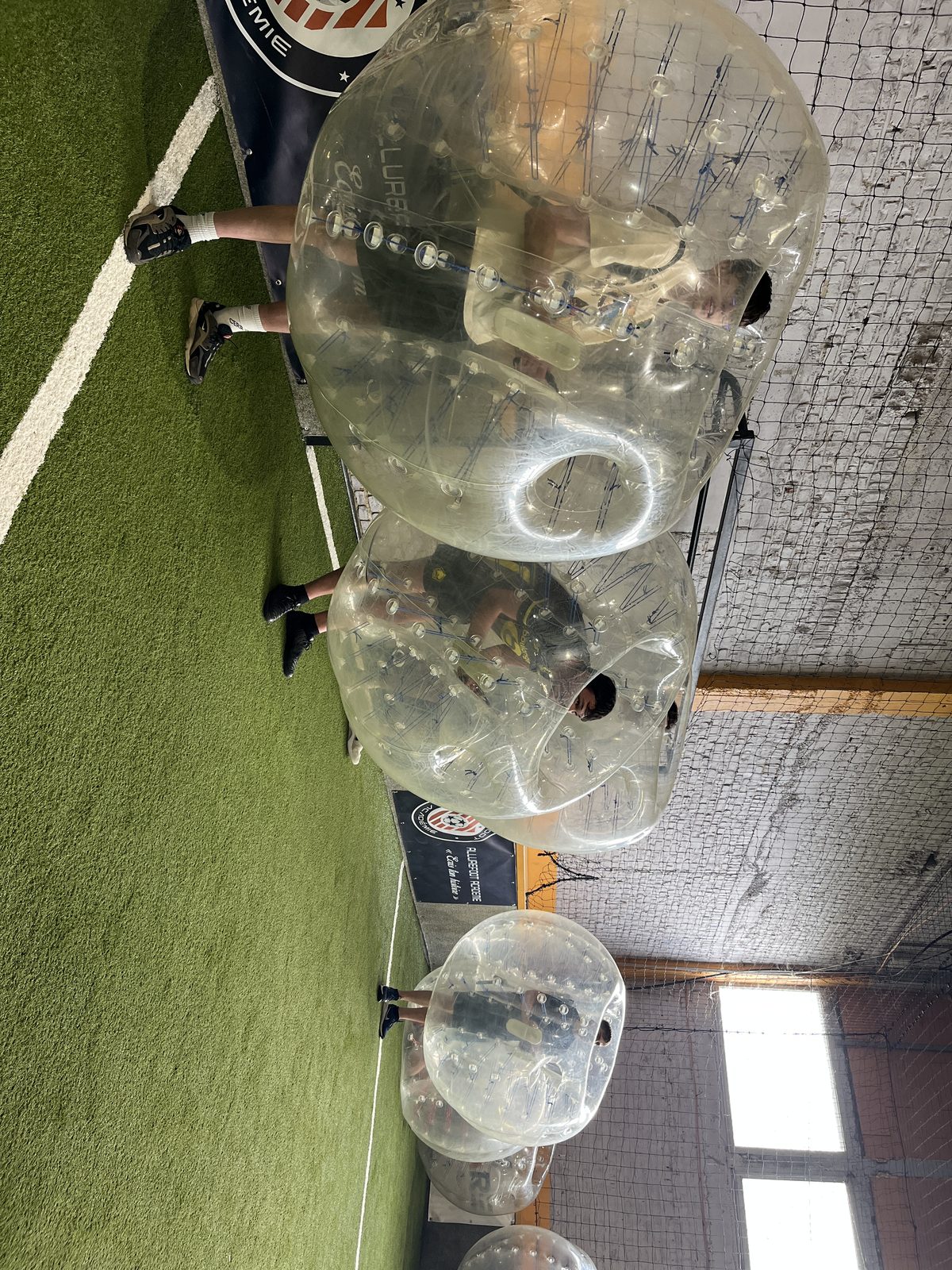 Deux joueurs se percutent sur le terrain de Bubble Foot indoor chez Team Square